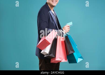 Close up of man  in suit holding credit card with shopping bags Stock Photo