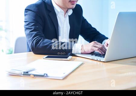 Close up view of businessman using laptop on wooden table. Stock Photo