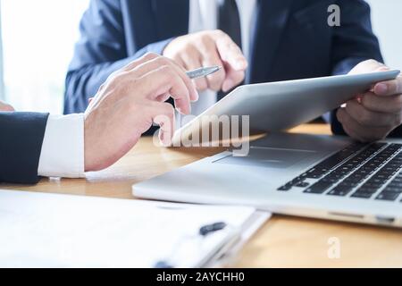 Two businessman using laptop and digital tablet to discuss finance and marketing solution . Stock Photo