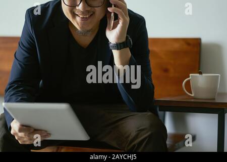 Closeup of businessman using smartphone and digital tablet . Stock Photo