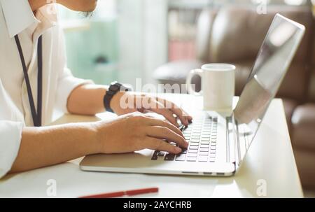 Businessman using laptop with tablet and pen on white table in office with a cup of coffee Stock Photo