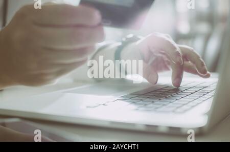Young man holding credit card and using laptop computer. Online shopping concept Stock Photo