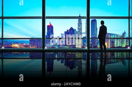 Back view of thoughtful businessman looking through window at big modern city Stock Photo