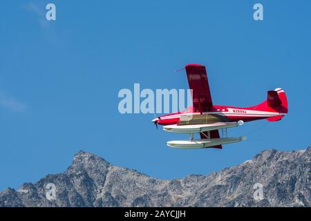 A red seaplane is flying over Lake Crescent in Lake Clark National Park and Preserve, Alaska, USA. Stock Photo