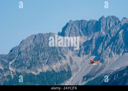 A red seaplane is flying over Lake Crescent in Lake Clark National Park and Preserve, Alaska, USA. Stock Photo