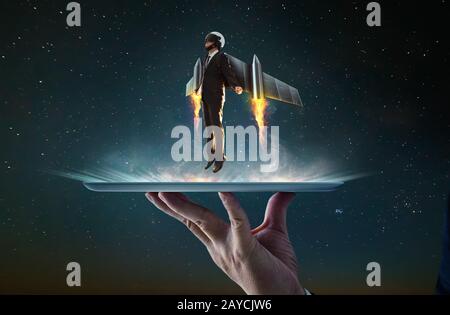 Waiter hand holding an empty digital tablet with Businessman wear a rocket suit to lift Stock Photo