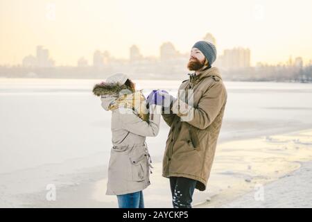 Young couple cheerfully flounders in snow. Between comic fight. Happy young couple hugs in winter snowy woods. Romantic lifestyl Stock Photo