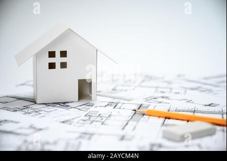 Construction industry concept with pencils and house models on architectural drawings. Stock Photo