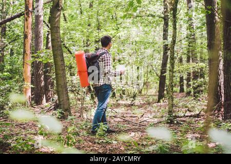Man with Backpack and map searching directions in wilderness area. Tourist with backpack using map in forest. concept tourism ho Stock Photo