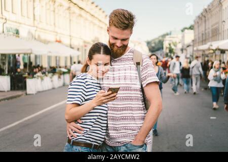 Couple tourists consulting city and mobile phone gps in street. People traveling. Couple checking location in smart phone. Techn Stock Photo