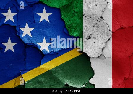flags of Solomon Islands and Italy painted on cracked wall Stock Photo