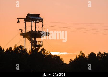 zipline tower with people silhouettes at sunset Stock Photo