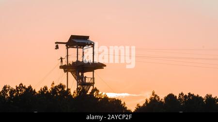 zipline tower with people silhouettes at sunset Stock Photo