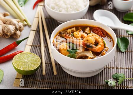 Tom Yum Goong spicy Thai soup with prawns, coconut milk and mushrooms. Tom Yum Kung served with rice. Traditional Thai food. Stock Photo