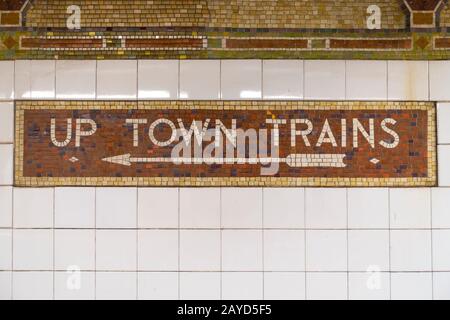 Manhattan, New York, USA. 03/27/2018 Sign made of tile reading up town trains with arrow pointing to viewer left side Stock Photo