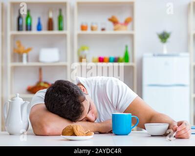 Man falling asleep during his breakfast after overtime work Stock Photo