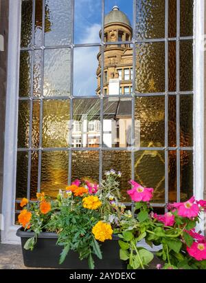 Reflection of an old classical building in the window of another classical building with a flower-po Stock Photo