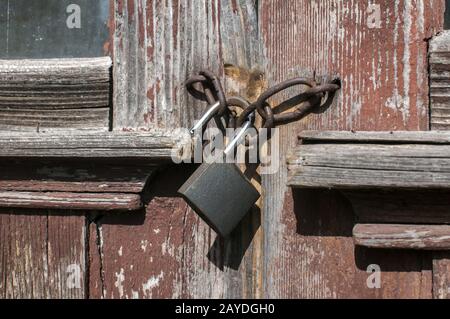 Old vintage weathered gunge locked padlock closeup on aged wooden door Stock Photo