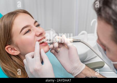 Dentist polishes teeth patient using a drill with a brush Stock Photo