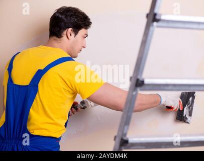 Young contractor employee applying plaster on wall Stock Photo