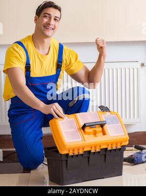 The young repairman contractor repairing heating panel Stock Photo