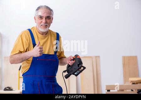 Old male carpenter working in workshop Stock Photo