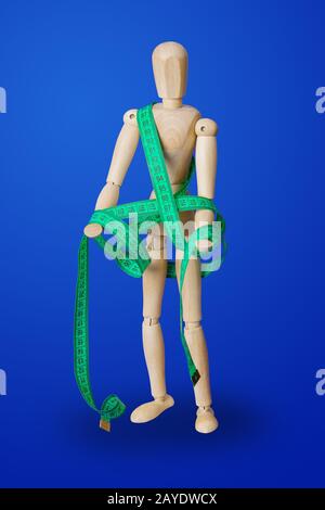 Wooden toy figure with measuring tape on blue Stock Photo