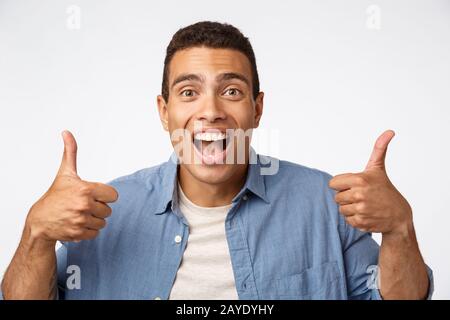 Enthusiastic good-looking young happy guy, showing thumbs-up, encourage someone, praise friend did good job, smiling nod in agre Stock Photo