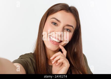 Portrait of a smiling cute woman making selfie photo on smartphone isolated on a white background. Stock Photo