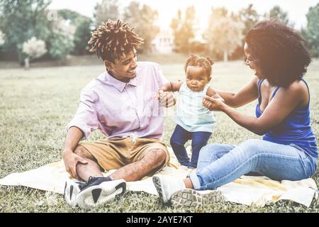 Happy black family having fun doing picnic outdoor - Parents and their daughter enjoying time together in a weekend day - Love tender moments and happ Stock Photo