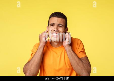 Turn off this annoying music, man hates christmas eve songs. Distressed and disturbed handsome guy, cringe and grimacing from bo Stock Photo