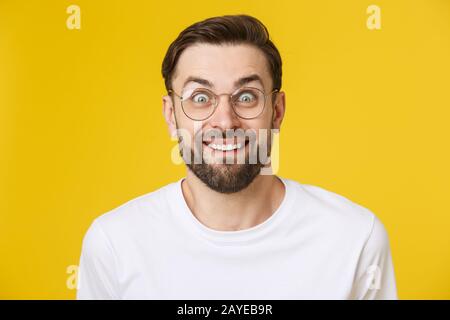Young man looking at copyspace having a surprised or satisfied look isolated on yellow background. Stock Photo