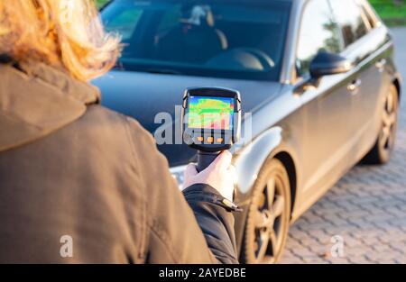 Woman shows with a thermal imager on a building to detect defects as an infrared image Stock Photo