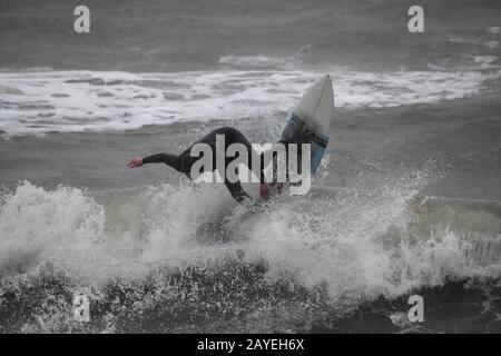 Gower, Swansea, UK. 15th February 2020. UK Weather: A surfer makes the most of the waves at Langland Bay, Gower, as Storm Dennis brings bad weather to Swansea in South Wales as the UK is hit by 70mph winds and heavy rain as another named storm disrupts the weekend. Credit : Robert Melen/Alamy Live News. Stock Photo