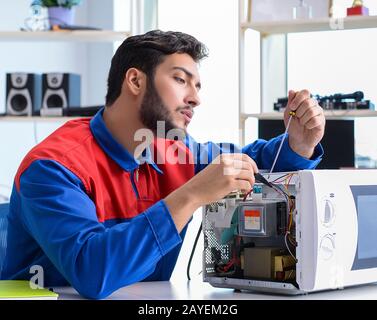 Young repairman fixing and repairing microwave oven Stock Photo