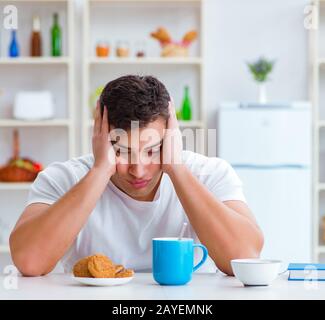 Man falling asleep during his breakfast after overtime work Stock Photo