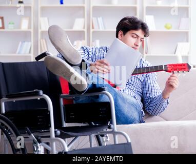 Disabled man playing guitar at home Stock Photo