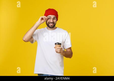 Man on isolated vibrant yellow color taking a coffee in takeaway paper cup and smiling because he will start the day well. Stock Photo