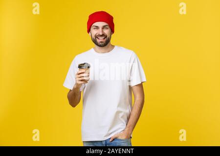 Man on isolated vibrant yellow color taking a coffee in takeaway paper cup and smiling because he will start the day well. Stock Photo