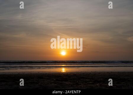 Sunset over an ocean with the waves breaking on the beach Stock Photo