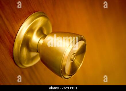 Golden, brass colored door opener, latch on a wooden door Stock Photo