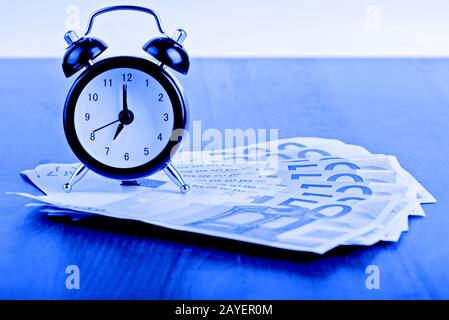 Business concept time is money. Alarm clock on the 50 Euro banknotes. Blue toned. Stock Photo