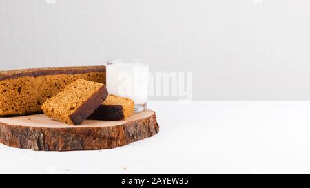 Traditional spice gingerbread cake with honey, ginger, cinnamon, nutmeg and annis from Holland with a glass of milk on a white background, banner Stock Photo