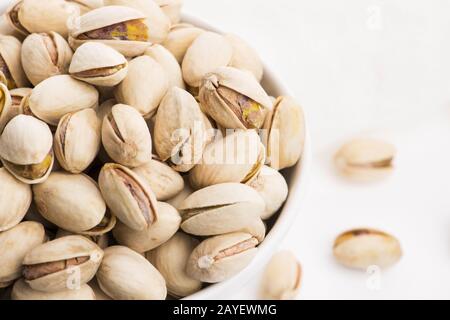 Bowl of roasted pistachios on a white background Stock Photo