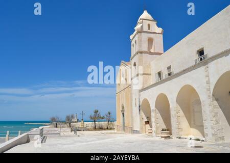 St Francis church, Vieste, Italy made of clear stone with the view of the sea and a bright blue sky Stock Photo