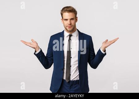 Make your choice. Serious-looking assertive and stylish young blond businessman in classic suit, propose two variants gain money Stock Photo
