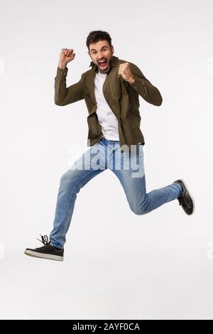 Achievement, congratulations and business concept. Full-length studio vertical shot attractive cheerful man jumping from triumph Stock Photo