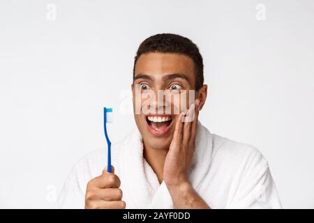 Man with tooth brush. African man holding a toothbrush with tooth brush and smiling while standing over white background. Stock Photo