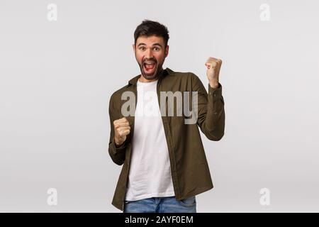 Relish, celebration and victory concept. Cheerful triumphing lucky businessman, guy winning, achieve prize or goal, have great n Stock Photo
