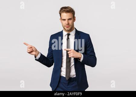 Serious-looking displeased, offended young blond businessman feeling sad, sulking, make grumpy face and looking from under foreh Stock Photo